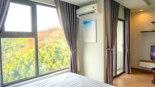 a bedroom with a bed and a large window at Ecobay Halong -Mountain view and near Marina beach in Ha Long