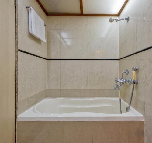 a bath tub in a bathroom with a shower at Hotel Royal Castle in Mumbai