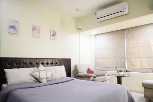 1 dormitorio con 1 cama y 1 silla en Lite Stays - Vile Parle East en Bombay