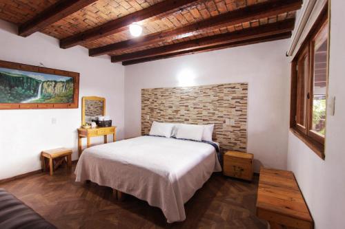 a bedroom with a bed and a brick wall at Real Carretero in Tapalpa