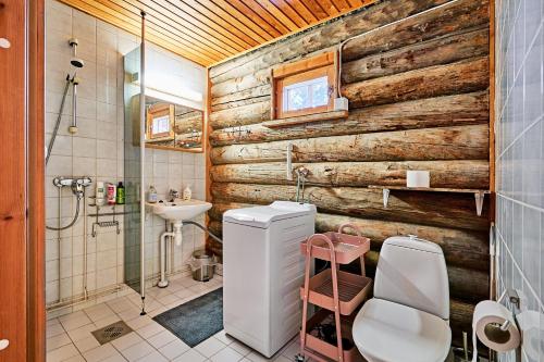 baño con pared de madera, aseo y lavamanos en Ski-inn kelohuoneisto Pyhätunturissa, en Pelkosenniemi