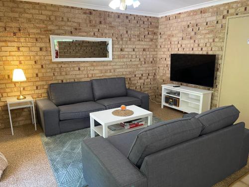 a living room with two couches and a tv at Esperance Holiday Apartment in Esperance