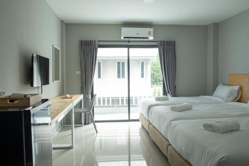 a bedroom with two beds and a desk with a television at Fine Bed Hotel in Nonthaburi
