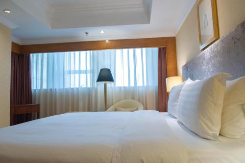 a bedroom with a large white bed with a window at Crowne Plaza Qingdao, an IHG Hotel in Qingdao