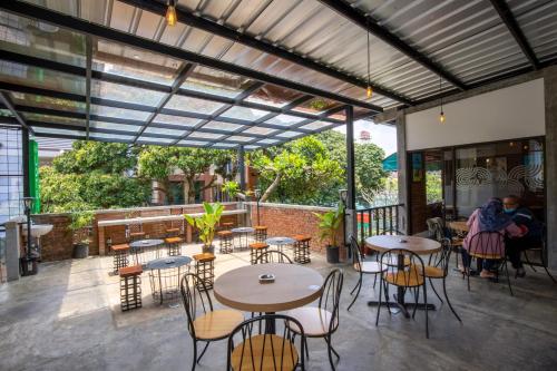 a patio with tables and chairs and people sitting at tables at Sekararum Butik Syariah Guesthouse in Bandung