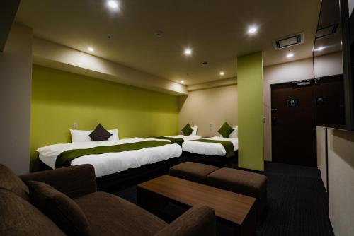 a hotel room with two beds and a couch at Randor Hotel Sapporo Suites in Sapporo