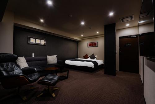 a hotel room with a couch and a bed at Randor Hotel Sapporo Suites in Sapporo