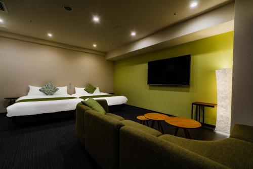 a hotel room with a bed and a flat screen tv at Randor Hotel Sapporo Suites in Sapporo