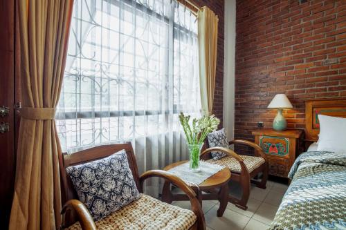 a room with a bed and chairs and a window at Sekararum Butik Syariah Guesthouse in Bandung
