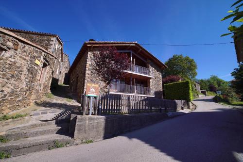 a stone house with a fence and a street at El carrero in Abella