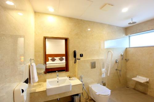 a bathroom with a sink and a toilet and a mirror at HOTEL AMALA in Pathanāmthitta