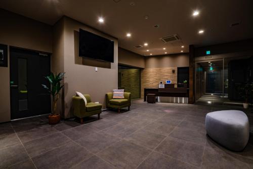 a lobby with chairs and a desk and a tv at Randor Hotel Sapporo Suites in Sapporo