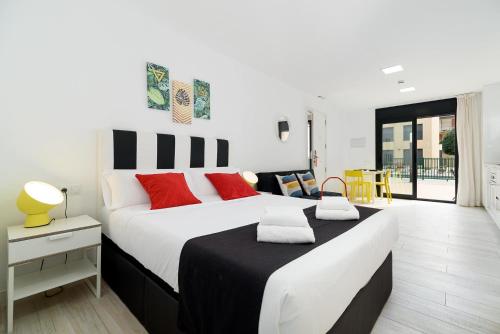 a bedroom with a large white bed with red pillows at Castell Beach Aparthotel in Castelldefels