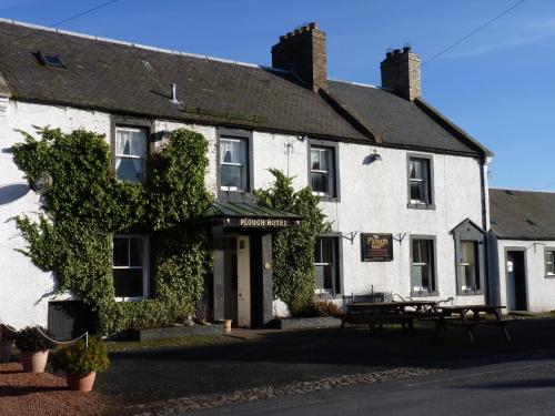a white building with a bench in front of it at Plough Hotel in Kirk Yetholm