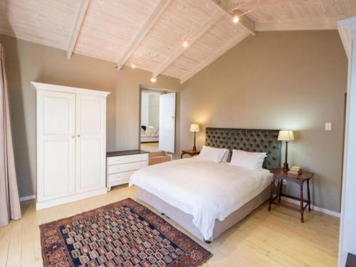 a bedroom with a large white bed and a rug at Wishford Cottage on Worcester in Grahamstown