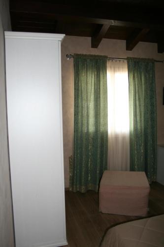 a bedroom with a bed and a window with green curtains at La Villetta Sul Mavone in Colledara
