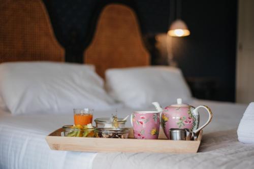a tray with cups and drinks on a bed at Hotel la Robeyere; BW Signature Collection in Embrun