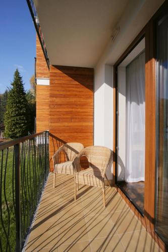 a balcony with two chairs on a wooden deck at Garden Hotel Domaša in Domaša Dobrá