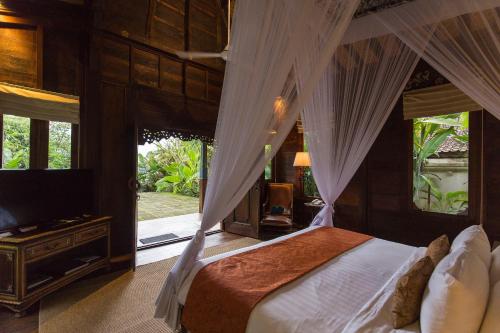 a bedroom with a canopy bed and a television at Plataran Borobudur in Borobudur