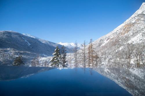 a view of a blue lake with snow covered mountains at QC Grand Hotel Bagni Nuovi in Bormio