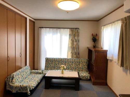 ein Wohnzimmer mit einem Sofa und einem Tisch in der Unterkunft Izu Shirada Villa 伊豆白田家 in Higashiizu