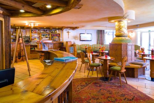 a restaurant with a bar and tables and chairs at Hotel Bellevue in Canazei