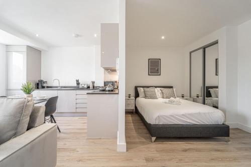 a white bedroom with a bed and a kitchen at Seven Living Residences Solihull - Close to NEC & BHX - Free Parking in Solihull