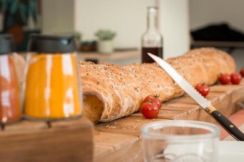 una hogaza de pan en una tabla de cortar con un cuchillo y tomates en Zenao Appart'hôtels Villeneuve-lès-Avignon, en Villeneuve-lès-Avignon
