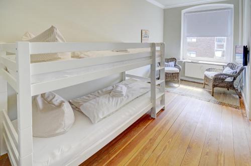 フレンスブルクにあるfewo1846 - Am Südermarkt - familienfreundliche Wohnung im Stadtzentrumのウッドフロアの客室で、白い二段ベッド1台が備わります。