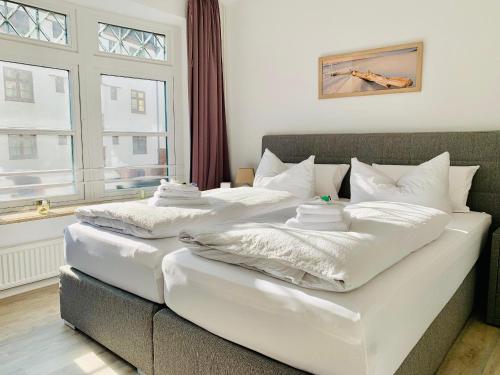 2 letti con coperte e cuscini bianchi in una stanza di fewo1846 - Atrium - luxuriöse Wohnung mit 3 Schlafzimmern und Balkon im Stadtzentrum a Flensburgo
