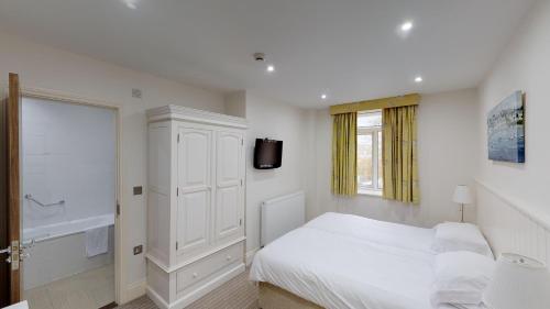 a bedroom with a white bed and white walls at Ommaroo Hotel in Saint Helier Jersey
