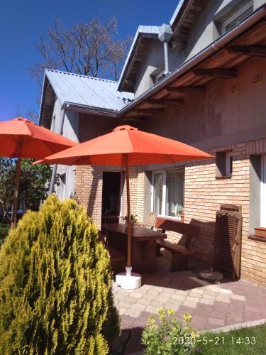 two red umbrellas and a picnic table on a patio at Willa Słoneczna - Magdalena i Michał Żelewscy in Karwieńskie Błoto Pierwsze