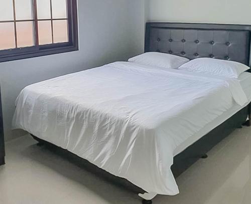 een bed met witte lakens en een blauw hoofdeinde bij Mahkota Residence Mitra RedDoorz in Karawang