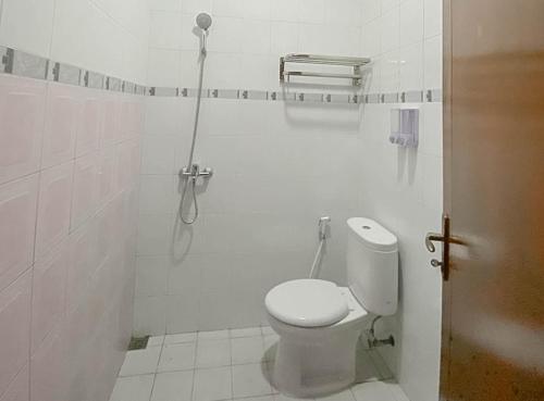 een witte badkamer met een toilet en een douche bij Mahkota Residence Mitra RedDoorz in Karawang