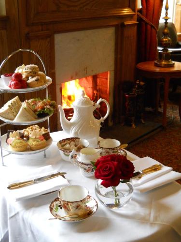 a table with a tea set with food and a fireplace at West Cork Hotel in Skibbereen