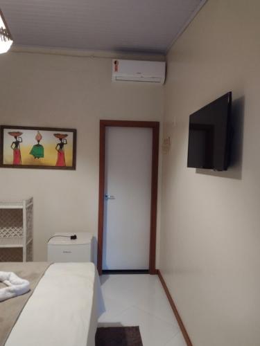 een slaapkamer met een bed en een flatscreen-tv bij Pousada Ilha do Meio in Itacimirim