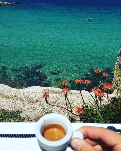 a person holding a cup of coffee next to the ocean at I Sottani in Monopoli