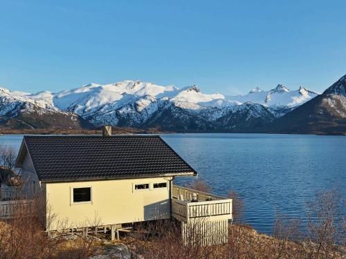 a house on the shore of a lake with snow covered mountains at 5 person holiday home in Laukvik in Laukvik