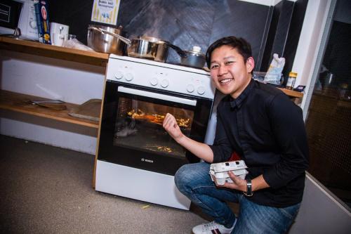 a man is sitting in front of an oven at Balmers Hostel in Interlaken