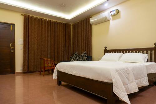 um quarto com uma cama grande e lençóis brancos em Pranaav Beach Resort em Pondicherry