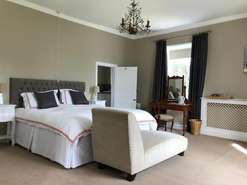 a bedroom with a large bed and a chair at Apuldram Manor farm in Chichester