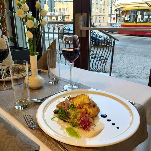 a plate of food on a table with a glass of wine at Holiday Inn Łódź by IHG in Łódź