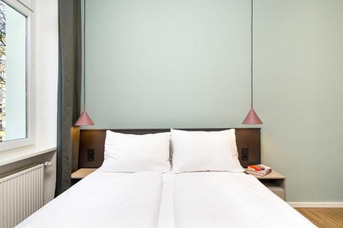 a bedroom with a bed with white sheets and pink lamps at BENSIMON apartments Mitte/Wedding in Berlin