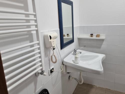 een witte badkamer met een wastafel en een spiegel bij La Boheme Hotel in Turijn