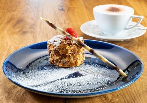 a dessert on a blue plate with a cup of coffee at Alpenhotel Tirol in Galtür