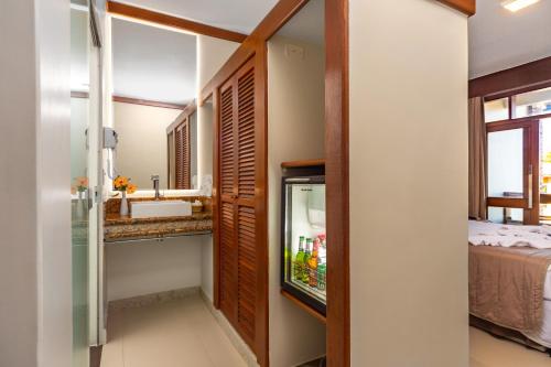 a bathroom with a sink and a refrigerator next to a bed at Quinta do Sol Praia Hotel in Porto Seguro