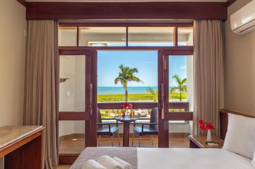 a bedroom with a view of the ocean at Quinta do Sol Praia Hotel in Porto Seguro