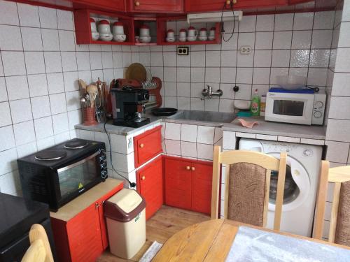 Апартамент Алекс في ديفين: مطبخ صغير مع خزائن حمراء وميكروويف