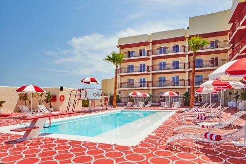 a pool with chairs and umbrellas next to a hotel at Romeos Ibiza - Adults Only in San Antonio Bay