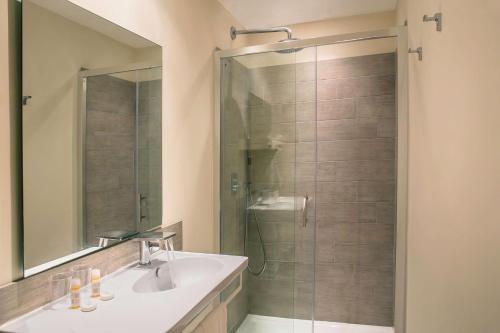 a bathroom with a shower with a sink and a mirror at Best Western Hotel du Roy d'Aragon in Bonifacio